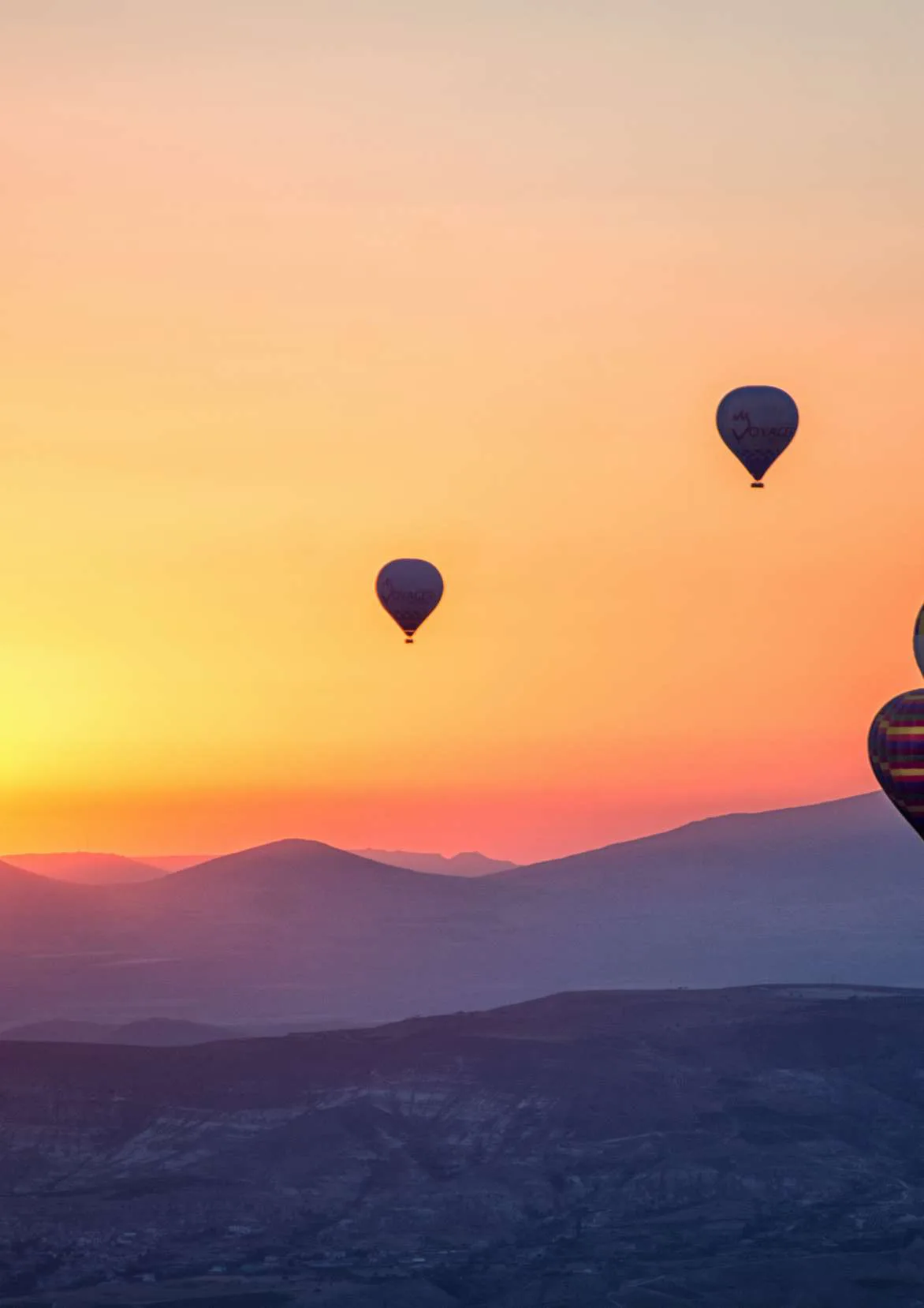 Sunset over hills with hot air balloons